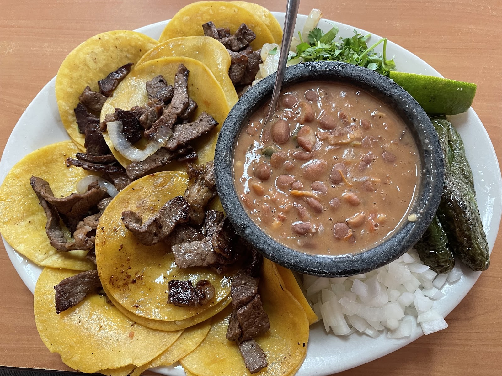 Carne asada tacos plate with molcajete beans, onion and lime at Sylvia's Mexican Restaurant