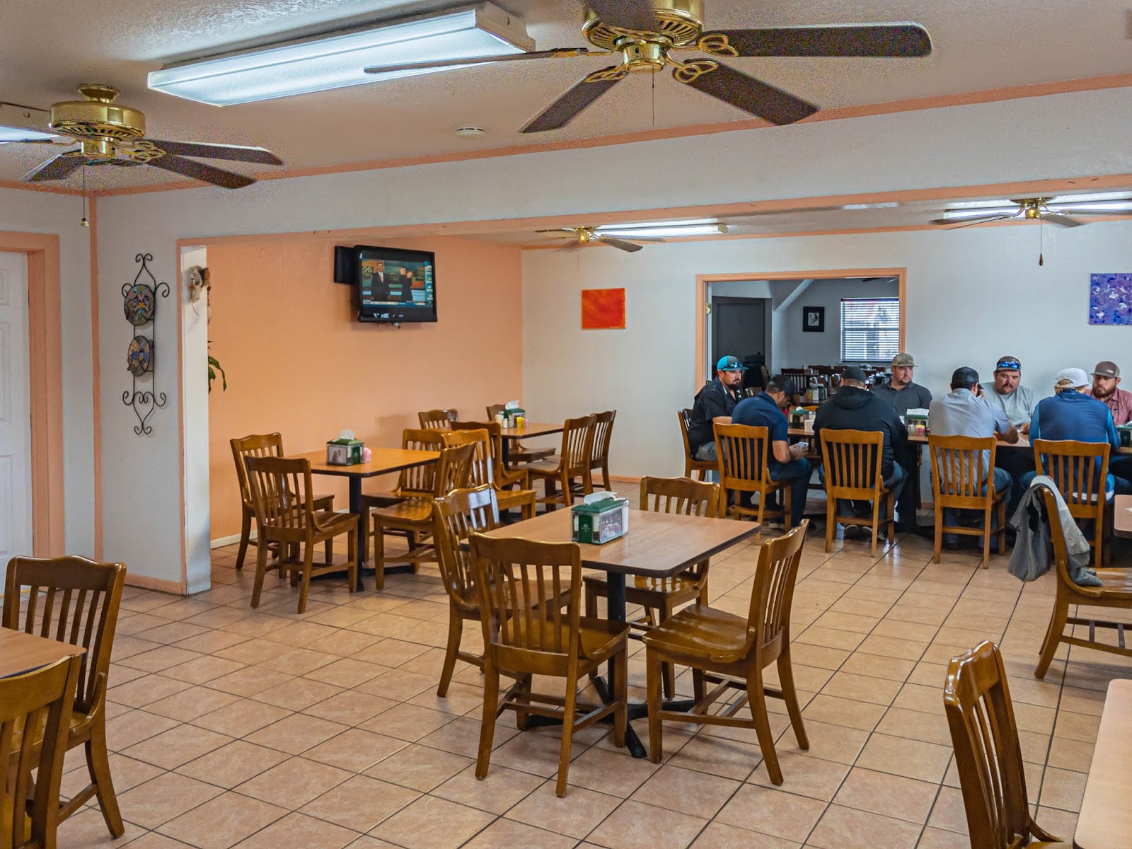 Cozy dining room with wood tables and ceiling fans at Sylvia's Mexican Restaurant